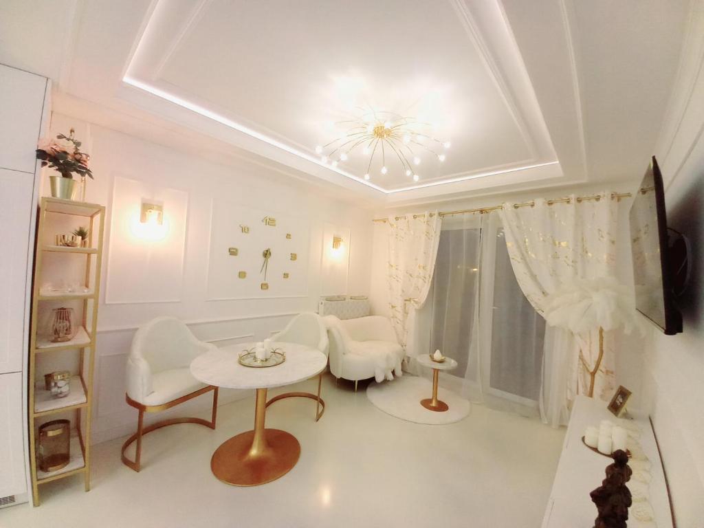 una sala de estar blanca con mesa y sillas en Apartament Glamour Okrzei, en Sandomierz