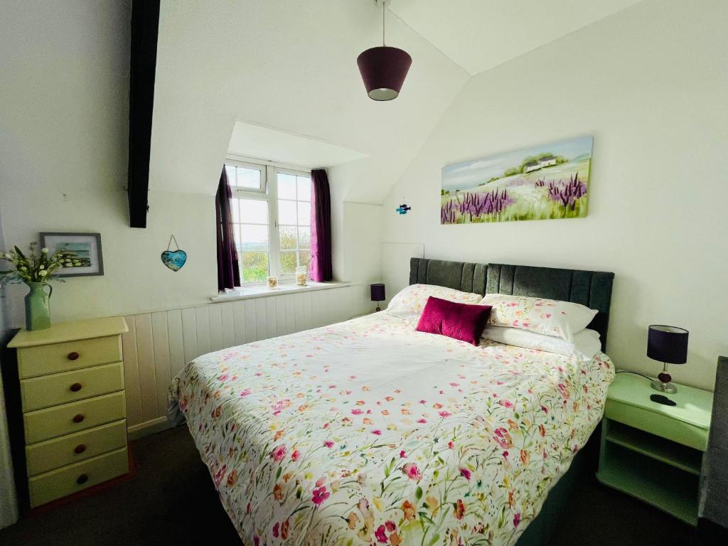 ein Schlafzimmer mit einem großen Bett mit rosa Kissen in der Unterkunft Honeysuckle Cottage in Ilfracombe