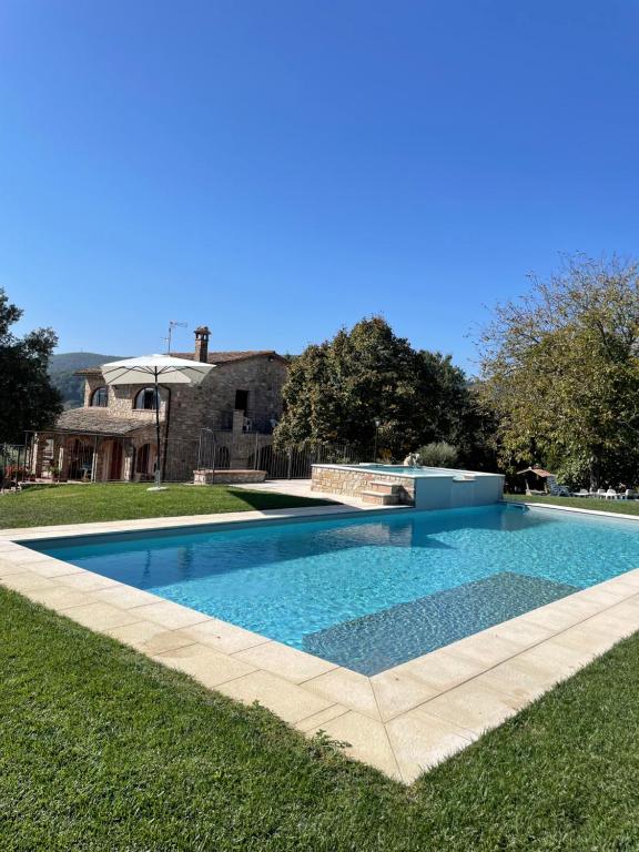 a large swimming pool in a yard with grass at Casale Il Fontanello in Todi