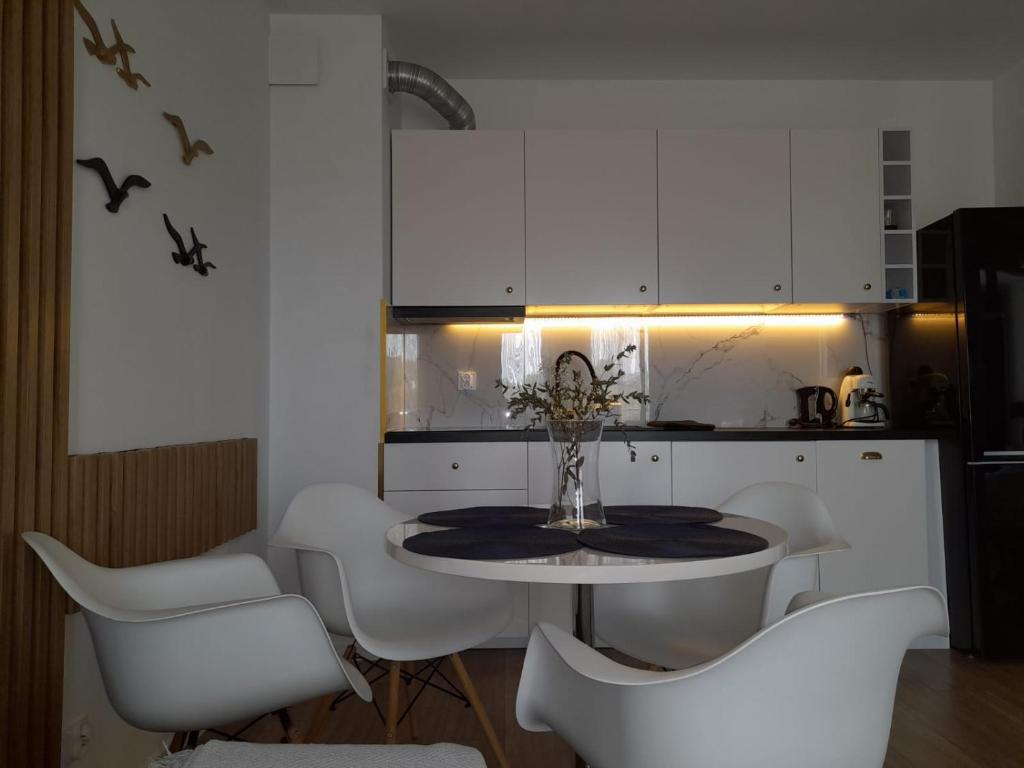 uma cozinha com armários brancos e uma mesa e cadeiras em DĘBOWA KUTNO em Kutno
