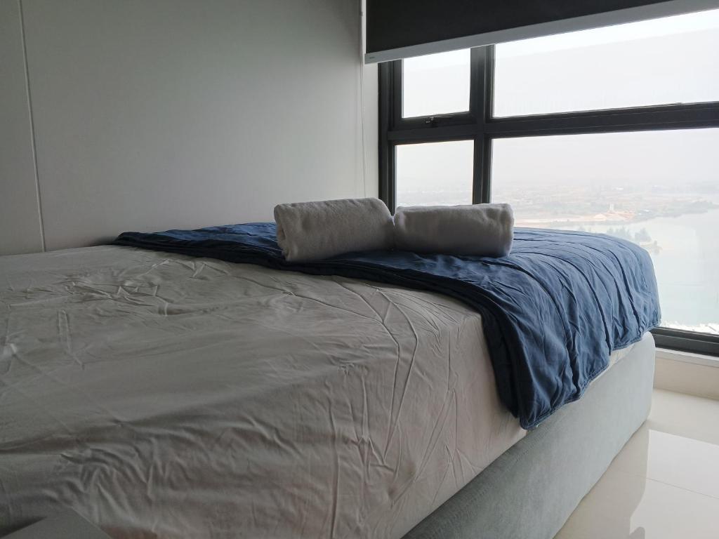 a bed with a blue blanket and a window at Peaceful Sea view Cozy APT at Batam Center - By MESA in Batam Center