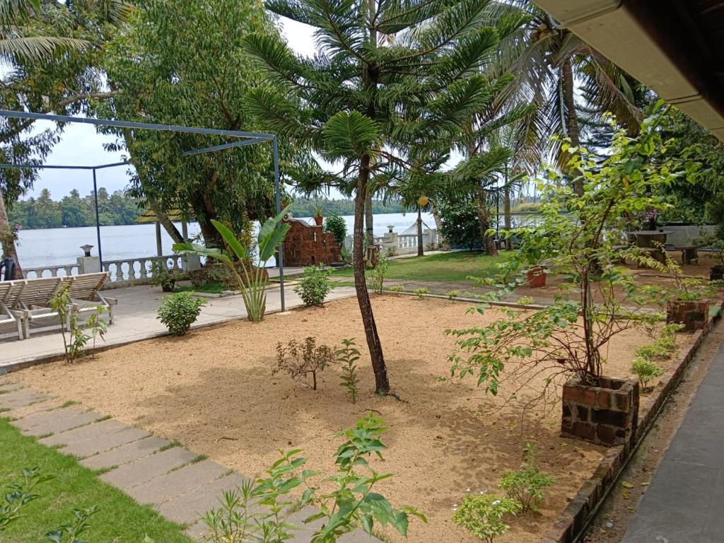 a garden with trees and a bench and water at Ambadi's villa -Lake view resort in Pallipuram