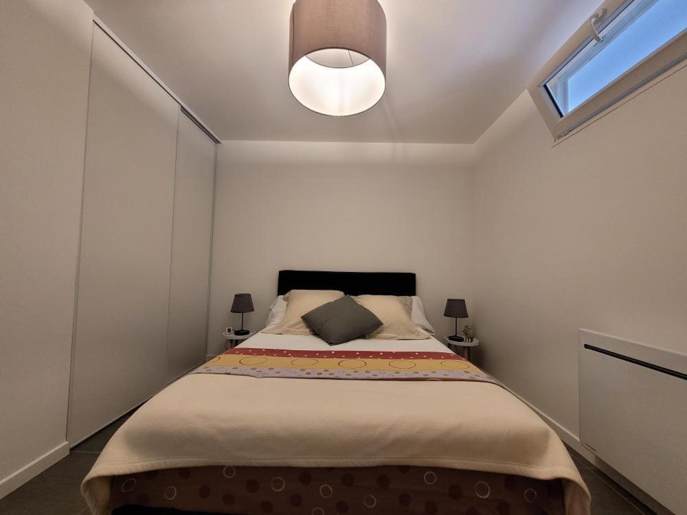 een slaapkamer met een groot bed met een licht erboven bij Appartement Salbris- Parking Gratuit in Salbris