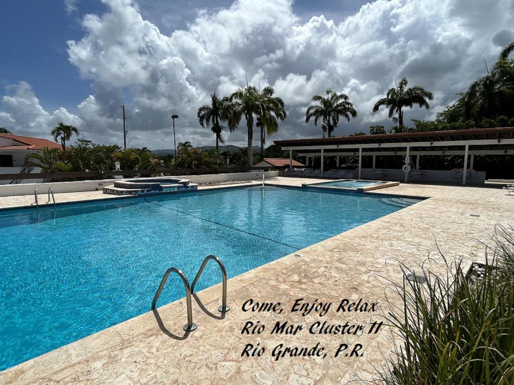 a swimming pool with a sign in front of a building at Come, Enjoy & Relax at Rio Mar Cluster II, Rio Grande, PR in Rio Grande