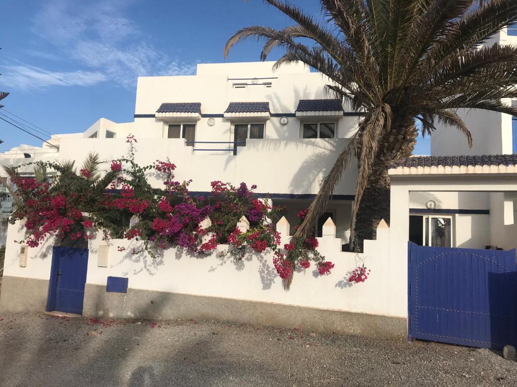 a white building with flowers on a fence at villa soleil in Mirleft