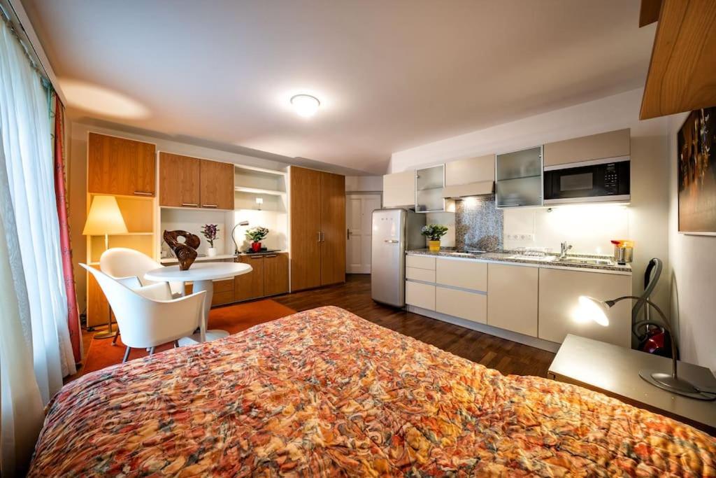 a bedroom with a bed and a table and a kitchen at Schlossquadrat Apartement 14 A in Vienna