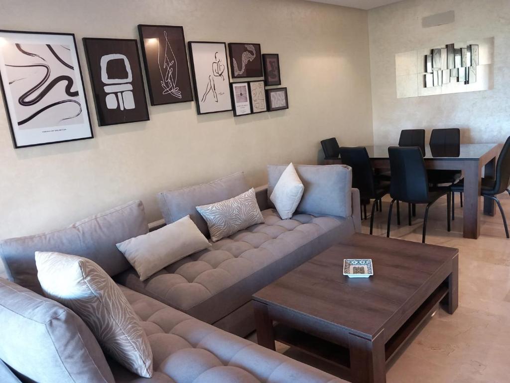 uma sala de estar com um sofá e uma mesa em Prestigia appt rez de jardin golf em Marrakech