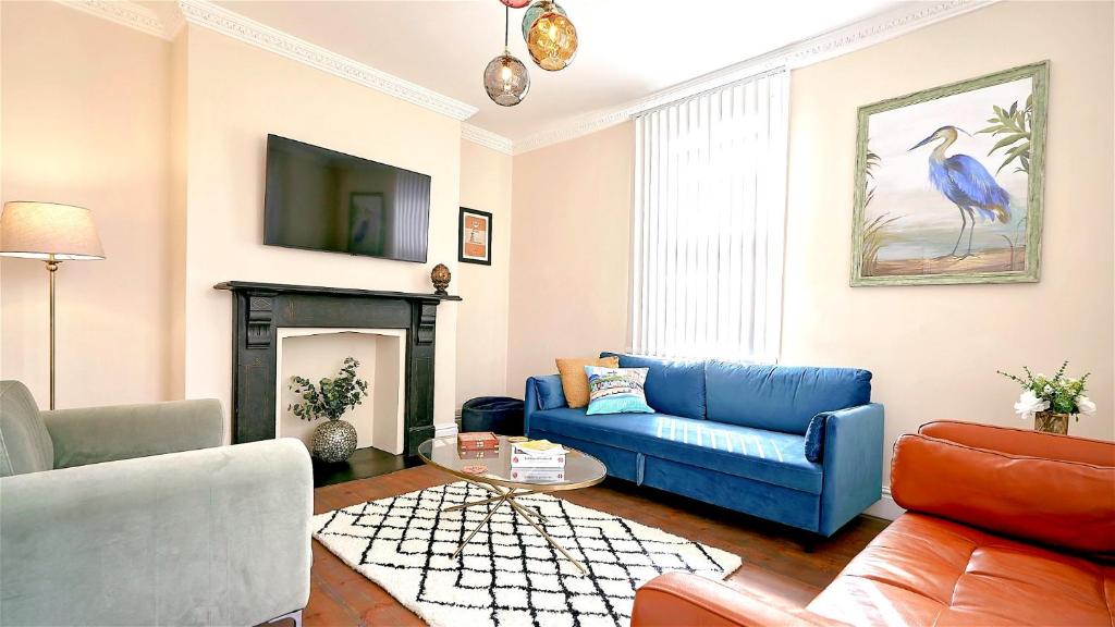 a living room with a blue couch and a fireplace at Hurn Crag House, Stunning ground floor apartment near Southwold in Southwold