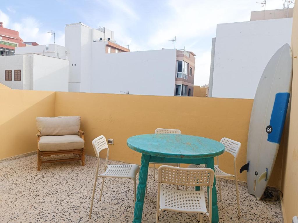 a table and chairs on a balcony with a surfboard at Daydream Medano Coliving in El Médano
