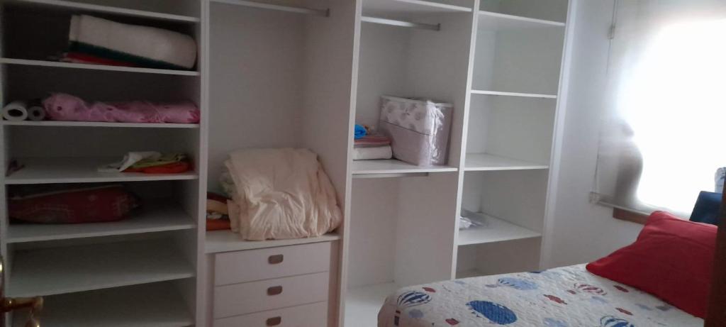 ein Schlafzimmer mit einem Schrank mit weißen Regalen und einem Bett in der Unterkunft Un rincon en barraña in Boiro