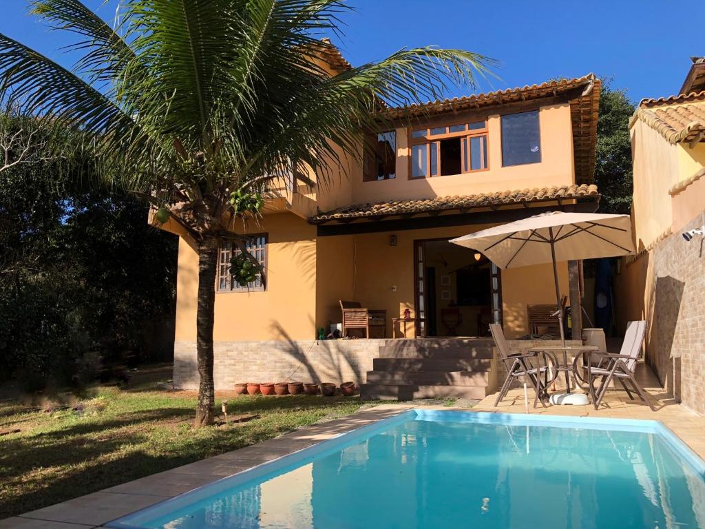 a house with a palm tree and a swimming pool at Excelente casa Búzios/Geribá in Búzios