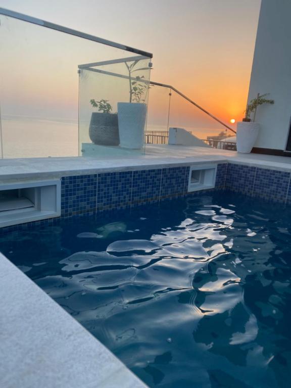 a swimming pool with a sunset in the background at Wadishab balcony in Ash Shāb