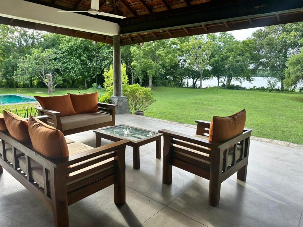 eine Terrasse mit Stühlen, einem Tisch und einem Pool in der Unterkunft Magalle Wewa Villa in Nikaweratiya