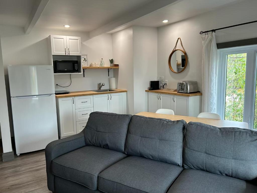 a living room with a couch and a kitchen at Petite Plaisance Appartements in La Malbaie
