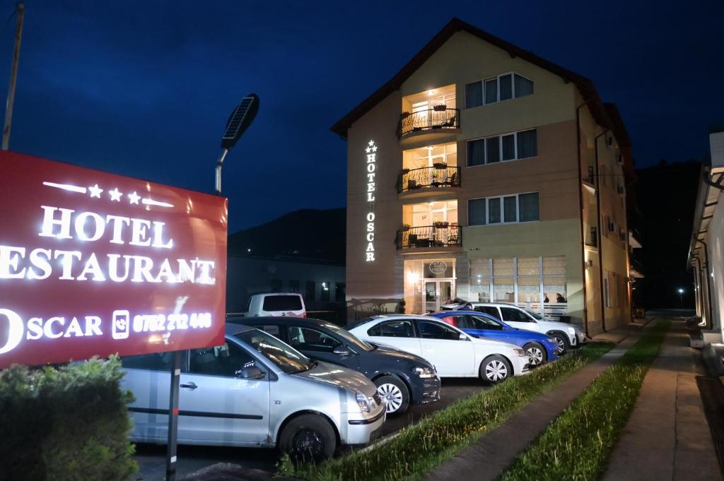 a hotel parking lot with cars parked in front of a building at Hotel-Restaurant Oscar in Piatra Neamţ