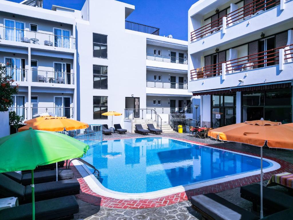 una piscina frente a un edificio con sombrillas en Poseidon Hotel, en Cos