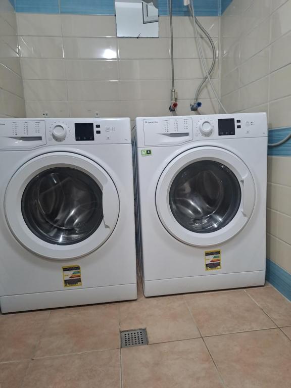 duas máquinas de lavar roupa sentadas uma ao lado da outra numa casa de banho em ALBERTI em Shëngjin