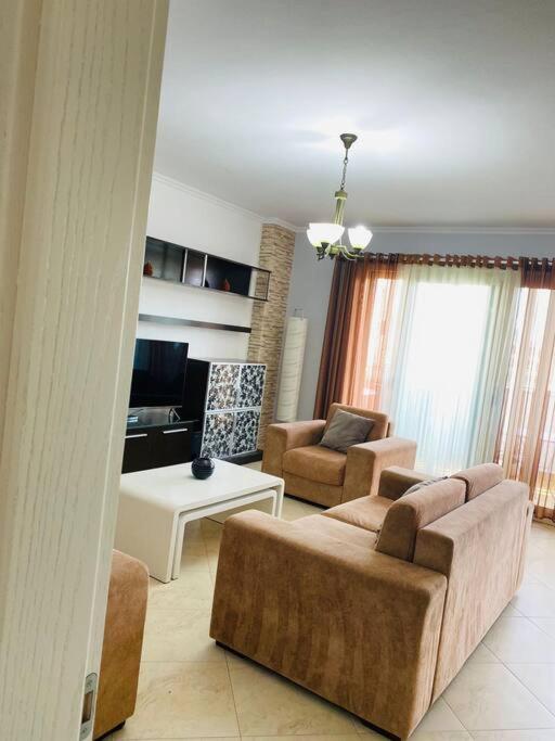uma sala de estar com um sofá, cadeiras e uma mesa em Cosy Apartment Tirana em Tirana