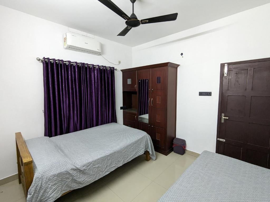 a bedroom with two beds and a ceiling fan at Budget Home in Cochin