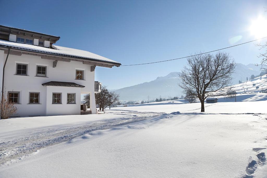 a snow covered road next to a white house at Gästehaus Weber in Oberperfuss