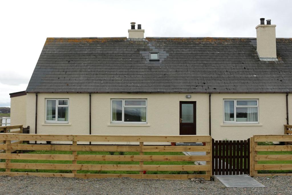 a house with a wooden fence in front of it at Stoneyfield South Cottage in Stornoway