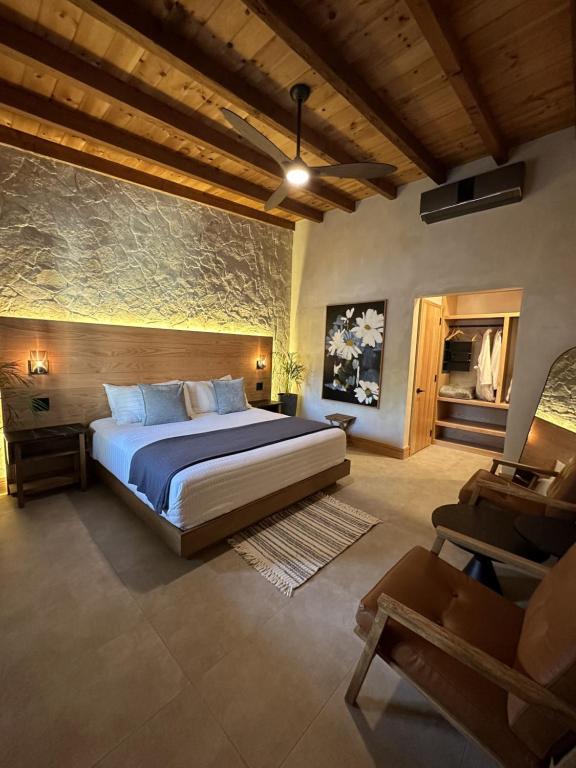 ein Schlafzimmer mit einem großen Bett und einem Stuhl in der Unterkunft MYA Hotel Boutique in Valle de Guadalupe