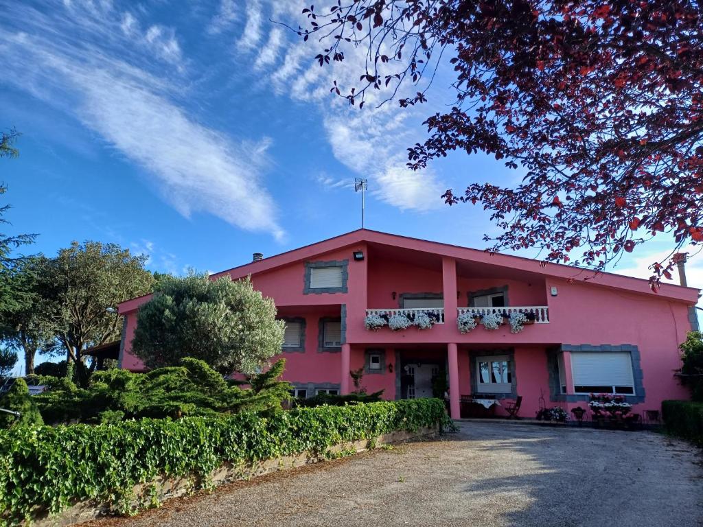 a pink building with a balcony on top of it at Finca Llamazares in La Bañeza