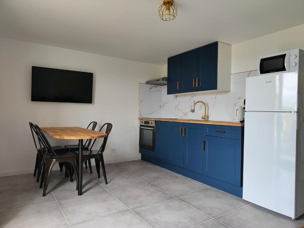 una cocina con armarios azules y una mesa con sillas en Le FAYA, en Pouzauges