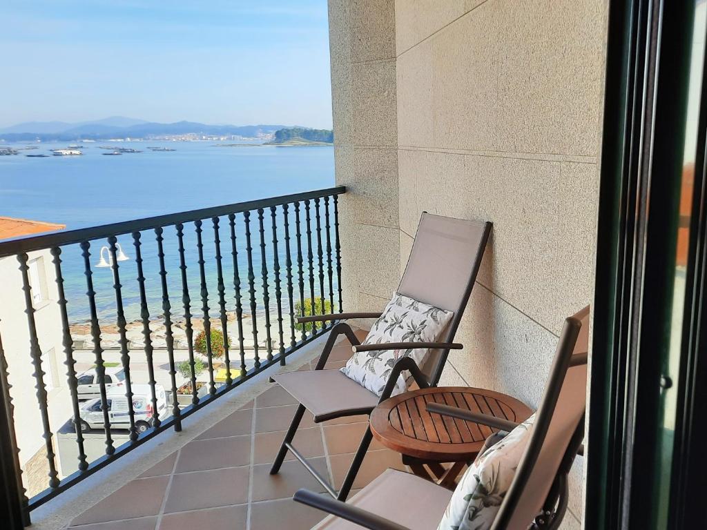 2 sillas en un balcón con vistas al agua en Apartamento en Beiramar, en O Grove