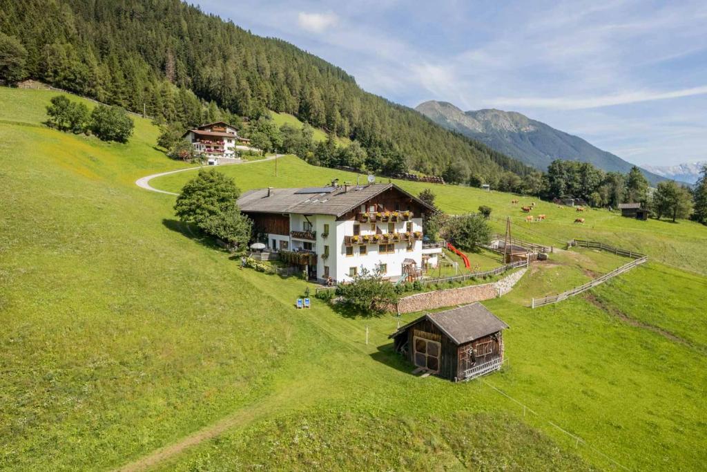 eine Luftansicht eines Hauses auf einem grünen Feld in der Unterkunft Omesbergerhof in Neustift im Stubaital