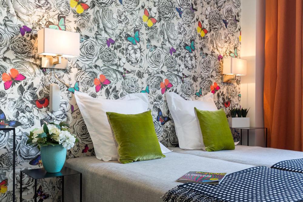 a bedroom with a bed with green and white pillows at Hôtel Victoria Châtelet in Paris