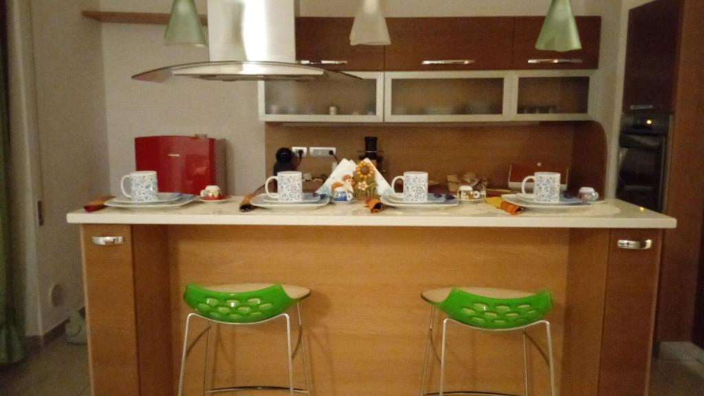 una isla de cocina con 2 taburetes verdes en Sweet holidays en Matera