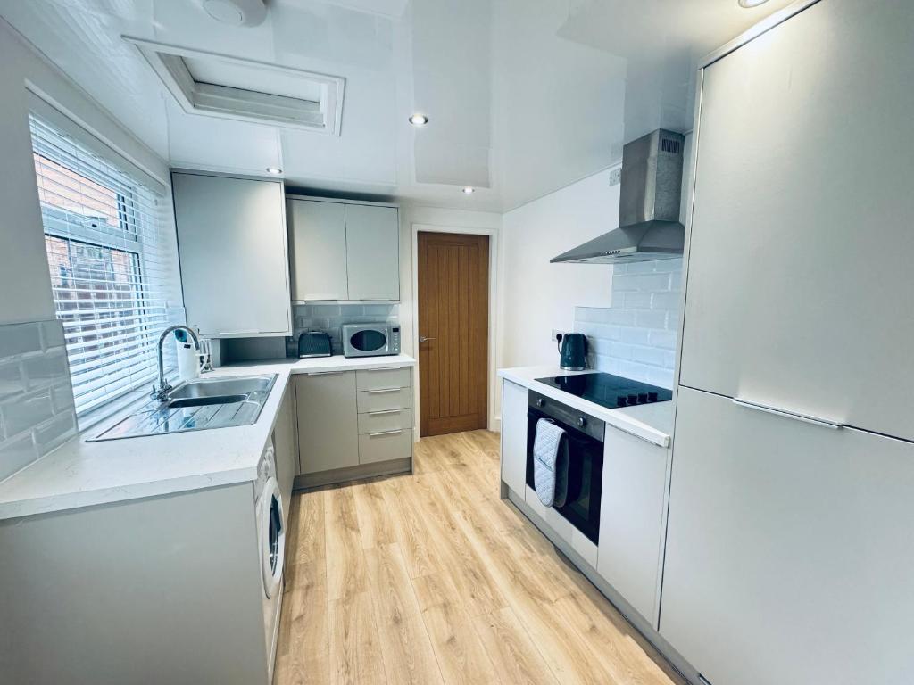 eine Küche mit weißen Geräten und Holzböden in der Unterkunft Rockcliffe Retreat, Stylish Coastal Apartment in Whitley Bay