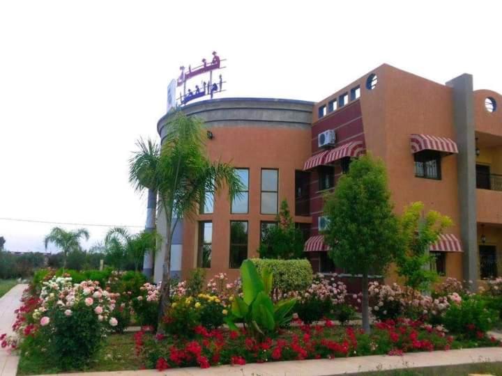 un edificio con un montón de flores delante de él en HOTEL OUM EL FADL, en Fkih Ben Salah