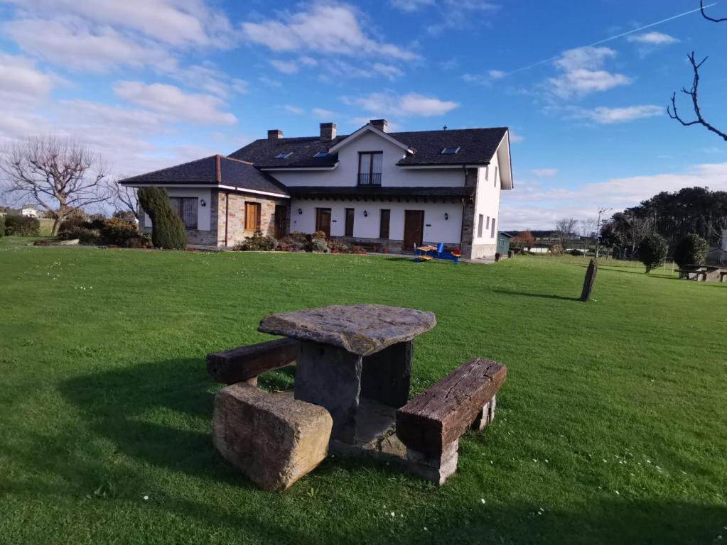 a stone bench in the grass in front of a house at Apartamentos La Cruz de Paderne in Navia
