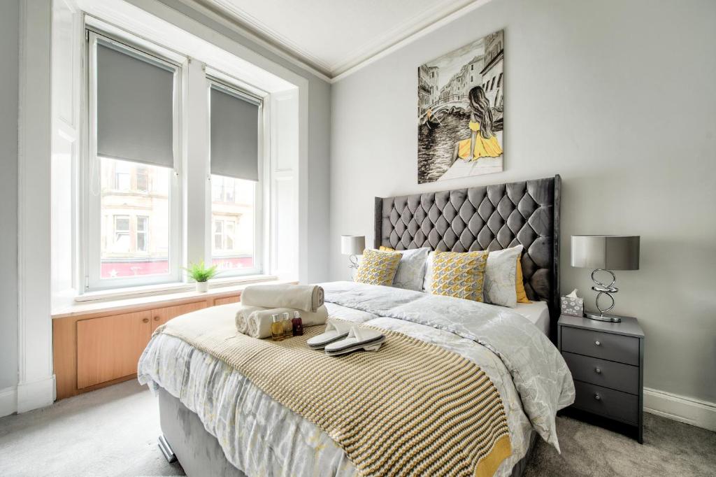 a bedroom with a large bed and two windows at Two Bed Stylish Apartment in Heart of West End in Glasgow