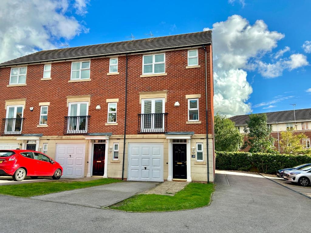 un edificio de ladrillo rojo con dos puertas blancas de garaje en The Town House, whole house suitable for contractors and families en Market Harborough