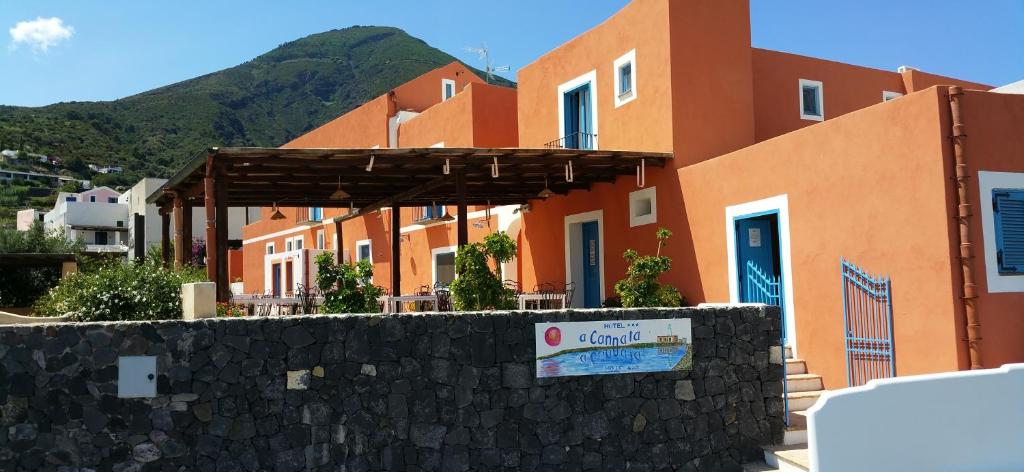 un bâtiment avec un mur en pierre devant lui dans l'établissement Hotel A Cannata, à Santa Marina Salina