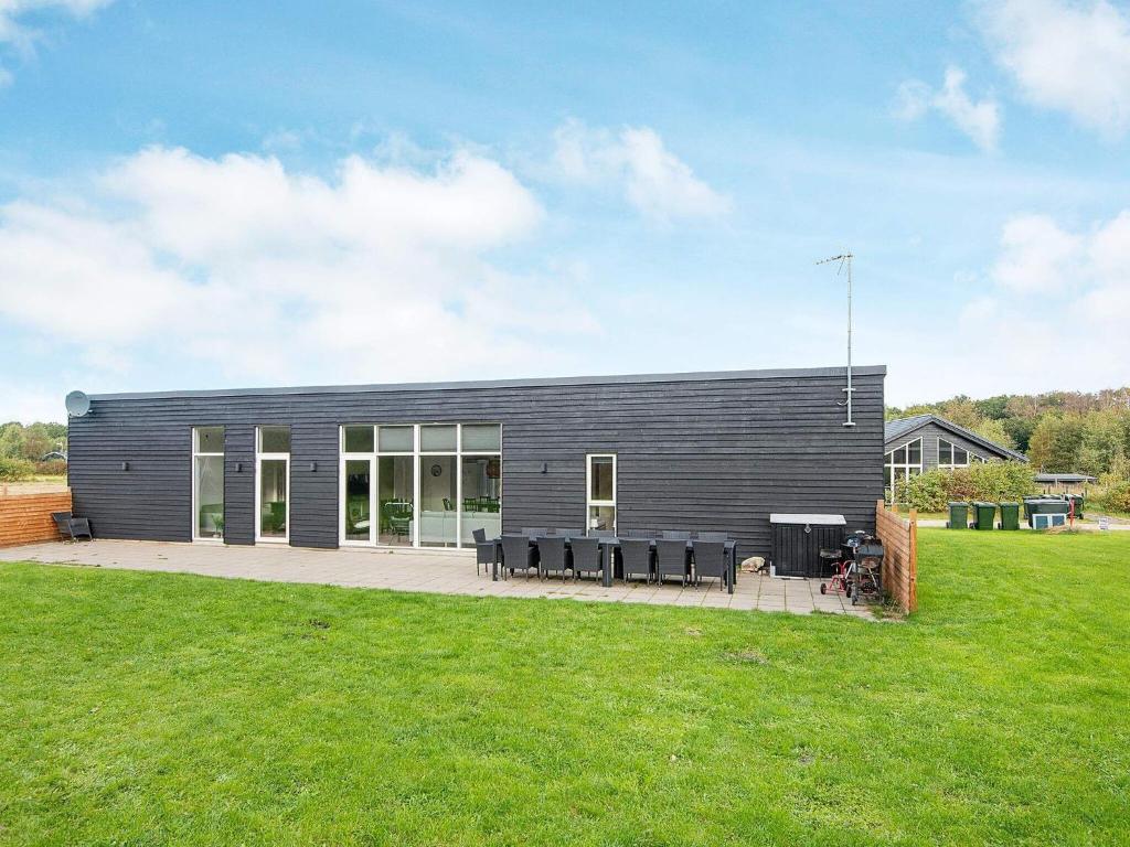 a gray house with a lawn in front of it at 14 person holiday home in Glesborg in Glesborg