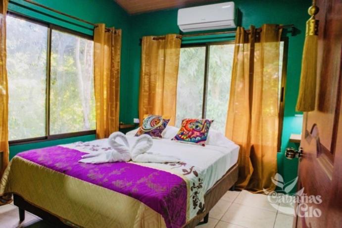 a bedroom with a bed with purple sheets and windows at Casita Verde, 800 mts from beach in Playa Hermosa