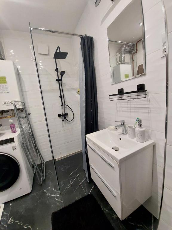 a white bathroom with a sink and a shower at Apartament Centrum 2 in Wałbrzych