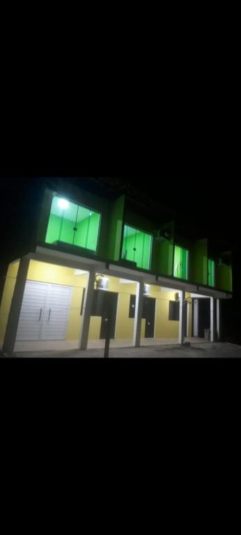 un edificio iluminado con ventanas verdes por la noche en Pousada Universo paralello pratigi, en Ituberá