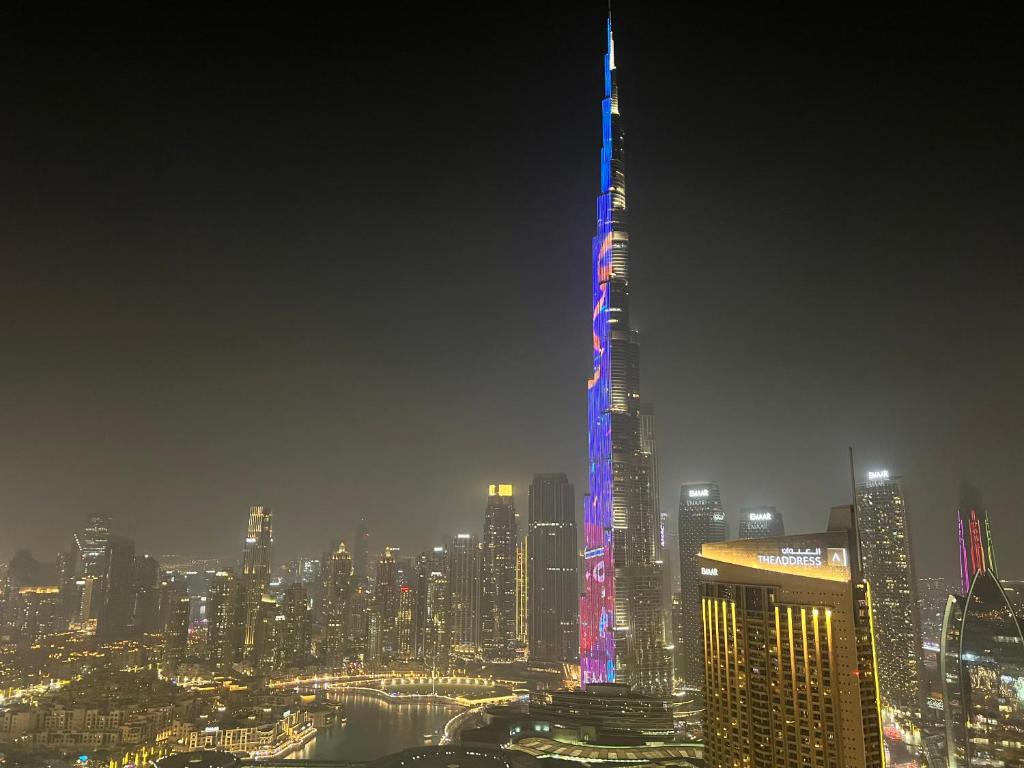 a tall skyscraper lit up in blue and purple at 3+1 BR, Burj Khalif, Dubai Mall in Dubai