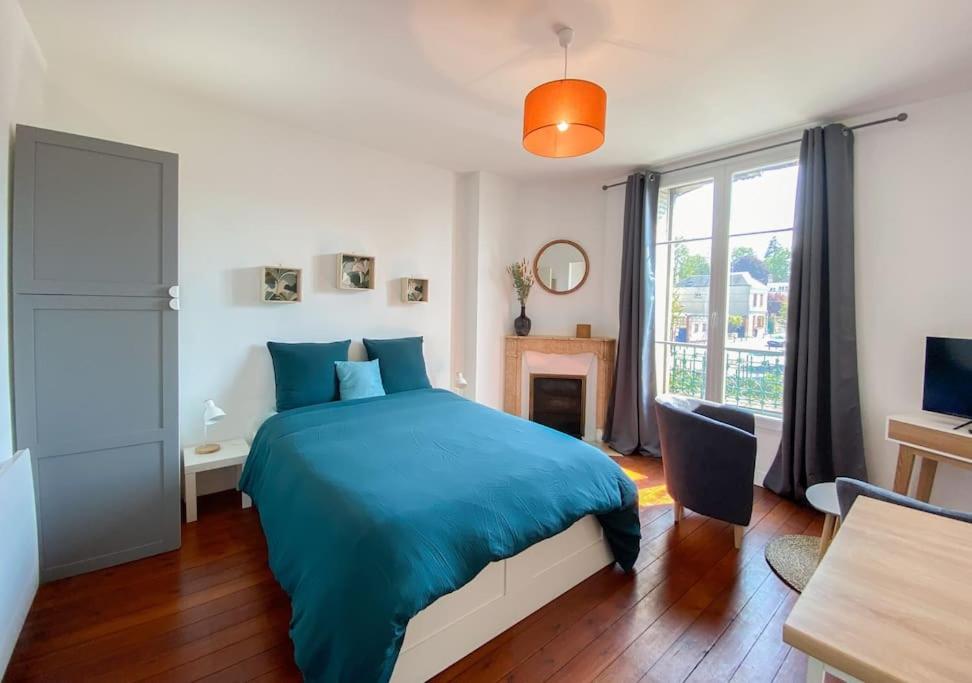 a bedroom with a blue bed and a window at Unique et élégant, gare hyper centre wifi in Vernon