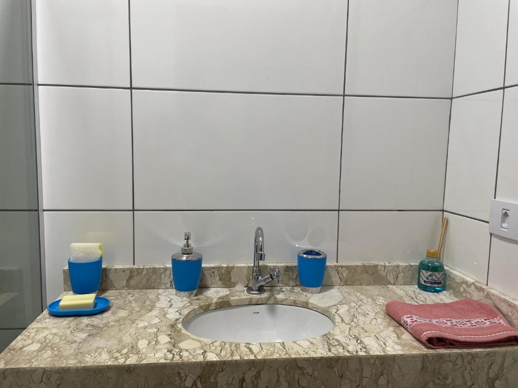 eine Badezimmertheke mit Waschbecken und blauen Tassen in der Unterkunft Casa completa e espaçosa in Foz do Iguaçu