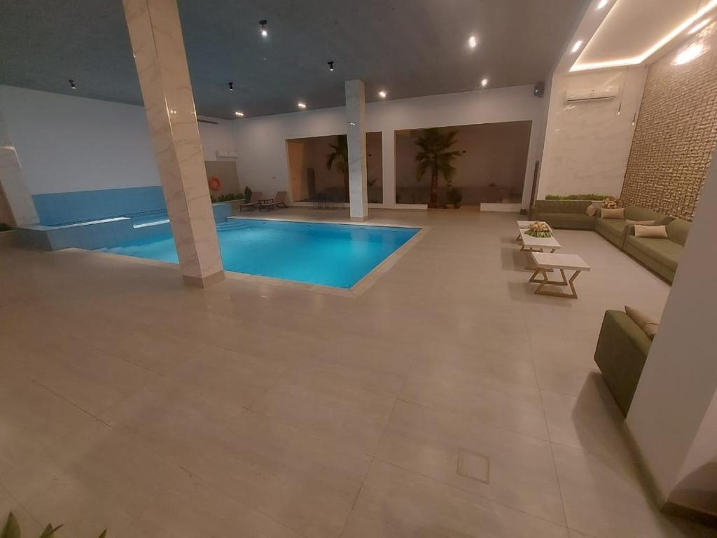 a large living room with a swimming pool in a building at غرف قاعة وشاليه ومسبح ماز in Al Rass