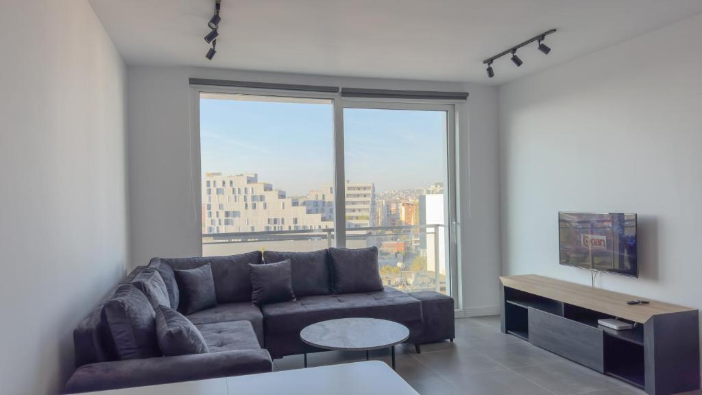 a living room with a couch and a large window at Urban Serenity Skyline View Apartment 2 in Tirana