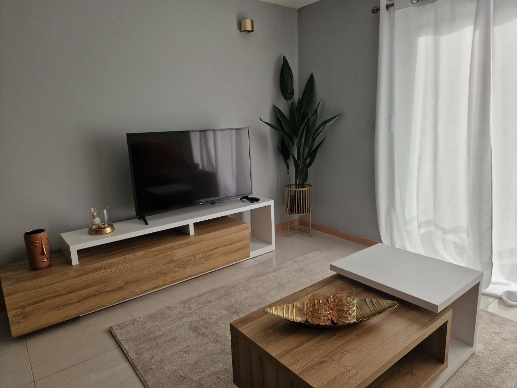 a living room with a flat screen tv on a stand at Aconchegante Refúgio Beira-Mar in Praia