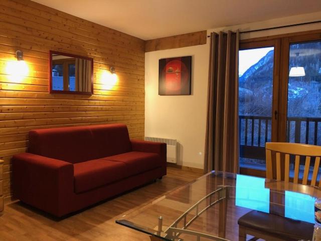 sala de estar con sofá rojo y mesa de cristal en Les 3 vallées - Piscine/Spa/Hammam - 4p, en Orelle