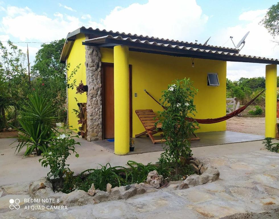 una casa amarilla con un banco delante en chalé caminho da mata, en Cavalcante
